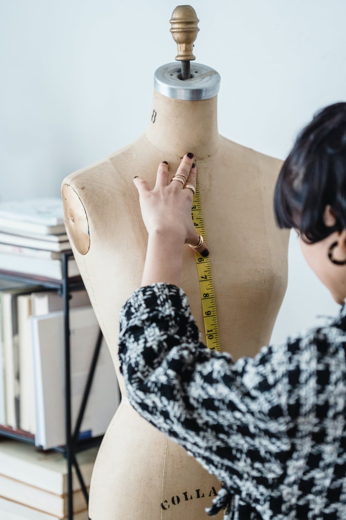 Mains prenant une mesure au mètre ruban sur un buste de couture